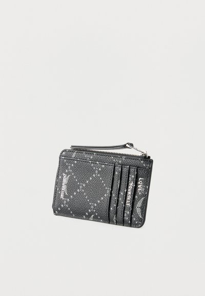 Μαύρος υφασμάτινος δερμάτινος θήκη για κάρτες με τσέπη με φερμουάρ, τρεις θήκες για κάρτες και λευκό τυπωμένο κείμενο που γράφει "Love Yourself" και "Amour".