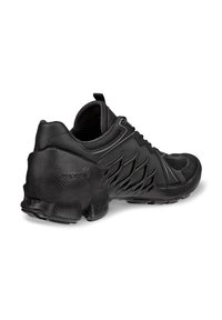Chaussure de sport noire avec une semelle en caoutchouc texturée, une tige en mesh et des éléments de design angulaires. Dotée d'une languette pour faciliter l'enfilage et d'accents de marque.