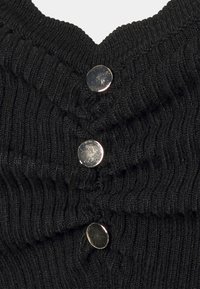 Schwarzes, gestricktes Oberteil mit einer gerippten Struktur, V-Ausschnitt und drei silbernen Druckknöpfen vorne, die das Design betonen.