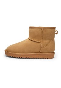 Light brown suede ankle boot with thick sole and ridged tread, visible stitching, and a loop pull tab at the heel.