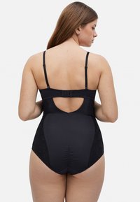 Bañador negro de una sola pieza con tirantes ajustables, un acento de encaje en los lados y una apertura en forma de llave en la parte posterior. Textura suave y diseño ajustado.