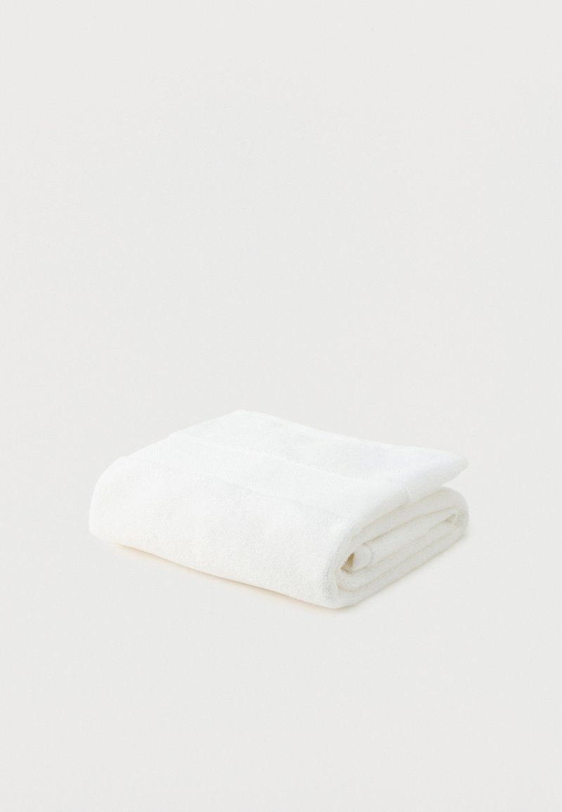 Soft white bath towel neatly folded on a plain white background.