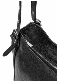 Czarna skórzana torebka o teksturowanej powierzchni, z metalowymi elementami w kolorze srebrnym, zamykana na zamek błyskawiczny i z regulowanym paskiem. Przedstawiony widok wnętrza.