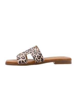 Sandalia plana tipo slide con suela marrón claro y tiras anchas de estampado de leopardo marrón con recortes geométricos sobre fondo blanco.