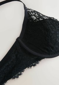 Black lace bra featuring floral patterns, a smooth underwire, and adjustable straps. The texture is delicate with sheer details.