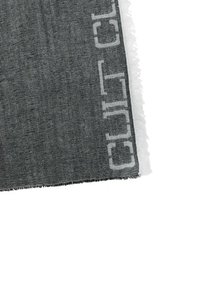 Tessuto tessuto grigio con bordo frangiato, caratterizzato da lettere bianche su un lato, che mette in risalto un tessuto texture e un design minimalista.