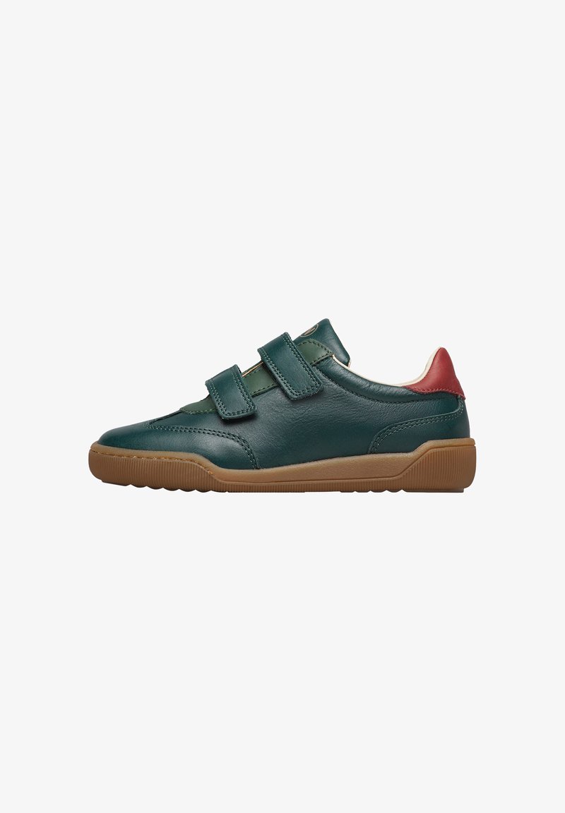 Scarpe in pelle verde con due cinturini in Velcro regolabili, punta arrotondata e suola in gomma marrone. Accento rosso sul tallone.