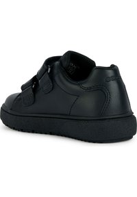 Scarpa in pelle nera con forma arrotondata, suola in gomma texture, e due cinturini a strappo per una vestibilità sicura. Marchio Geox visibile.