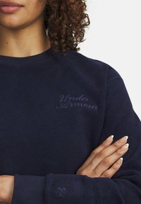 Maglione navy blu in tessuto testurizzato, con logo ricamato "Under Armour" in filo abbinato sul petto e dettaglio del logo sulla manica.