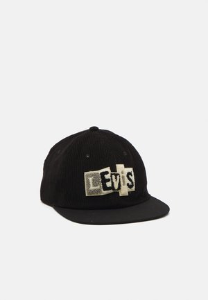 Casquette de baseball noire en velours côtelé avec une visière plate, ornée d'un écusson avec des lettres texturées blanches et noires formant le mot "Levi's" à l'avant.