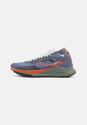 Blå og orange Nike trail løbesko med hvide snørebånd, grå sål og sort slidbane, vist fra siden på en hvid baggrund.