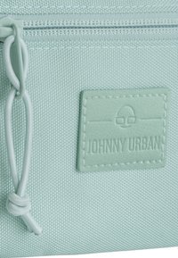 Světle mátově zelený textilní sáček s texturovaným povrchem, vybavený zipem a reliéfním štítkem s nápisem "JOHNNY URBAN."
