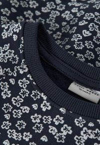 Marineblaues Sweatshirt mit weißem Blumenmuster. Mit geripptem Halsausschnitt und weichem Material. Etikett: "basic needs by namnit."