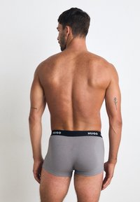 Boxer briefs grigi con un cinturino nero sul quale è stampato il nome del marchio "HUGO". Il materiale sembra soffice e presenta un design aderente.