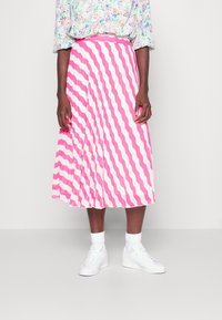 Saia midi plissada com listras onduladas em rosa e branco, com uma cintura ajustada, usada com ténis brancos e meias de cano curto.