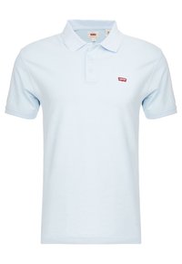 Ljusblå polo skjorta i bomull, med klassisk krage, tre knappar och en liten röd logotyp på vänster sida. Korta ärmar.