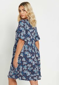 Marinblå blommig klänning med korta ärmar, med ljusblå blommor och prickar. Lös passform med utsvängd nederkant och fickor.
