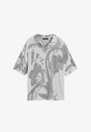 Lühikeste varrukatega polo särk hallist kangast, millel on lillemuster. Klassikaline krae koos kahe nööbiga, mugav istuvus ja pehme tekstuur.