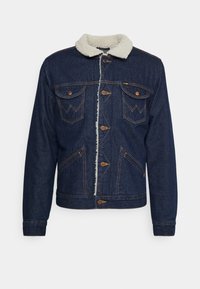 Tmavě modrá denimová bunda s krémovým límcem z umělé ovčí vlny, předními knoflíky, dvěma náprsními kapsami a kontrastními stehy.