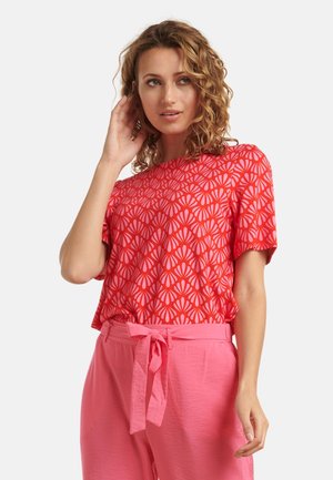 Rode korte mouwen top met een bloemenpatroon in lichtere tinten, gecombineerd met roze hoge taille broeken met een strikriem.