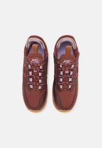 Nike Air superge v globoko rdeči in temno sivi mrežasti tkanini, z teksturiranim dizajnom, belimi vezalkami in podplatom iz gumijaste gume.