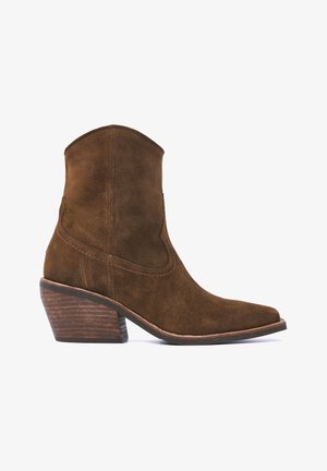 Bottes basses en daim marron avec un bout pointu, dotées d'une tige incurvée, de coutures décoratives et d'un talon en bois d'environ 6,5 cm de hauteur.