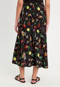 Jupe midi noire avec des graphiques colorés et ludiques présentant des motifs de soleil et de plantes. Ceinture élastique et tissu fluide pour un confort optimal.