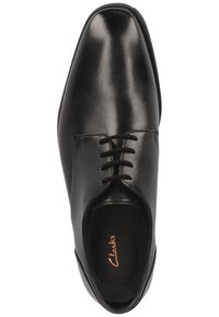 Chaussure de ville pour homme en cuir noir avec lacets, bout légèrement carré et marquage "Clarks" à l'intérieur de la semelle.