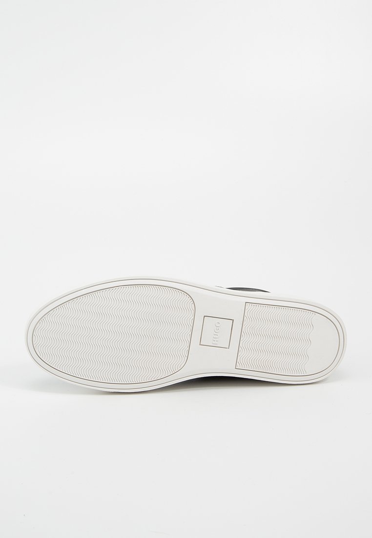 Schwarzer Sneaker mit einer weißen Gummisohle. Die Sohle weist ein wellenförmiges Texturmuster und ein rechteckiges Logo-Element auf.