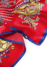 Écharpe en soie rouge ornée de motifs colorés de coquillages et de faune marine, avec une bordure bleue et une petite étiquette de marque sur le bord.