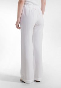 Valkoiset, leveälahkeiset housut, jotka on valmistettu teksturoidusta kankaasta. Niissä on joustava vyötärönauha ja sivutasku, ja design on puhdas sekä minimalistinen.