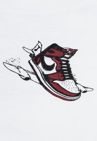 Raudoni ir juodi sportbačiai grafikoje ant balto audinio, su išsamiai aprašytu batų dizainu, raišteliais ir juodu logotipu. Animaciniuose akcentuose matyti dūmai.