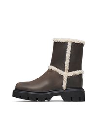 Stivali ankle in pelle marrone con un morbido accento in shearling crema, suola nera spessa e dettagli a motivo incrociato sull'esterno.