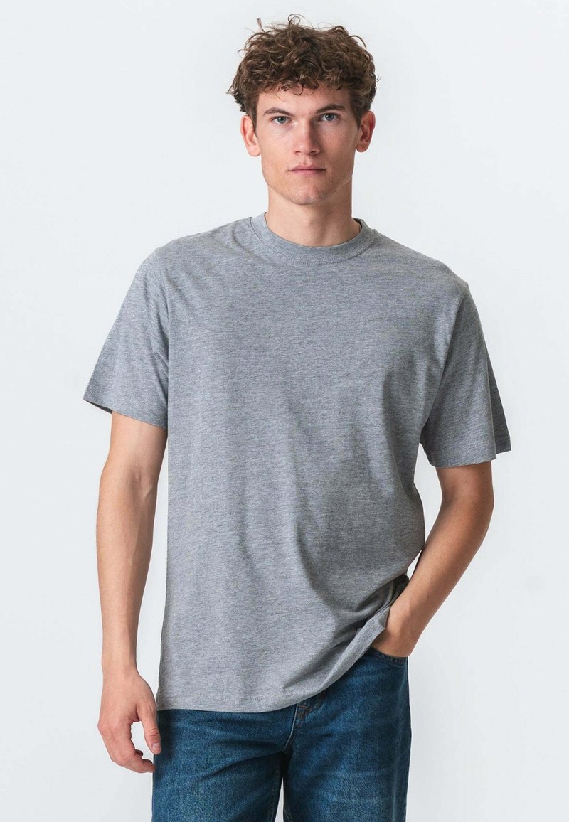 Grå kortærmet t-shirt med rund halsudskæring, lavet af blødt stof, med en afslappet pasform og glat tekstur. Bæres med blå jeans.