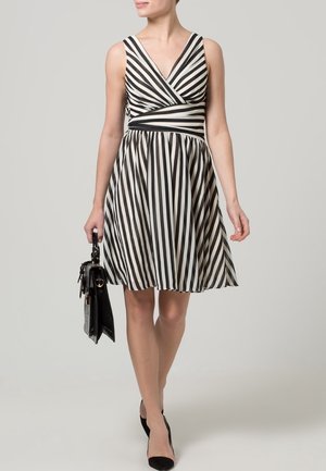 Šaty s černobílými pruhy, které mají přiléhavý korzet, výstřih do V a rozšířenou sukni. Modelka nese černou kabelku a má na sobě černé baleríny.