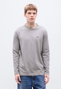 Γκρι πουκάμισο με μακριά μανίκια και στρογγυλή λαιμόκοψη, με μικρό μαύρο λογότυπο «BOSS» στο πάνω αριστερό μέρος του στήθους. Μαλακό ύφασμα και χαλαρή εφαρμογή.