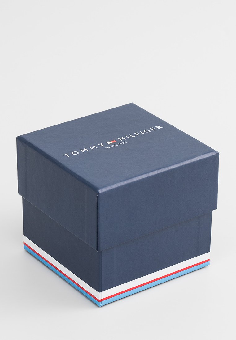 Granatowo-niebieskie pudełko kartonowe z przykrywką, z nazwą marki "TOMMY HILFIGER" oraz akcentem w czerwono-biało-niebieskie paski na dole.