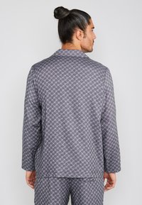 Grijze pyjama-set met een geometrisch patroon. Het langermige shirt heeft een reverskraag. Zachte stof met een gladde textuur. Eenvoudig, onversierd ontwerp.