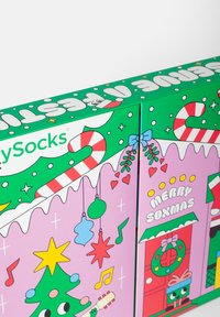 Zielono-różowe opakowanie z świątecznymi wzorami, które obejmują cukierki, ozdoby, choinkę oraz tekst "WESOŁY SOXMAS".