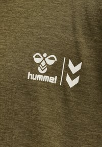 Olivengrøn stof med et hvidt trykt logo af en bi og ordet "hummel", ledsaget af to nedadpegende chevrons.
