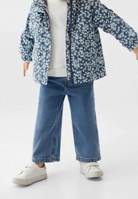Floral patterned, navy blue puffer jacket with elastic cuffs, paired with light blue wide-leg denim jeans and white velcro sneakers.