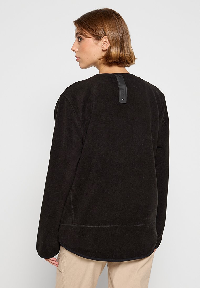 Felpa nera in pile con scollatura rotonda, maniche lunghe e una texture liscia. Presenta un distintivo dettaglio a strap sul retro per la chiusura.