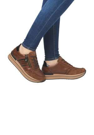 Braune Sneakers aus Wildleder und Leder, mit einem Reißverschlussdetail, kontrastierenden schwarzen Akzenten und einer gepolsterten Sohle mit gestreiftem Design.