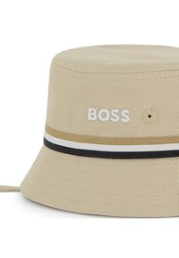Μπεζ καπέλο τύπου bucket από βαμβάκι με ανάγλυφη υφή, φέρει μαύρη και λευκή ριγέ ταινία και κεντητό λογότυπο "BOSS" στο μπροστινό μέρος.