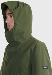 Giacca verde con cappuccio, dalla texture liscia, con chiusura a bottoni e un logo ricamato sulla manica. Design casual con colletto aderente.