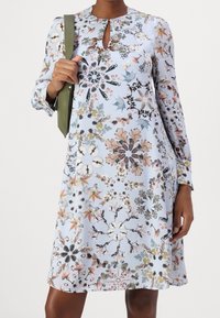 Vestido de estampado floral en azul claro, con un escote redondo y detalle de abertura, y mangas largas. Hecho de una tela suave, de corte relajado.