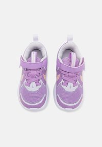 Chaussures de sport violettes avec des empiècements en mesh et en synthétique. Les caractéristiques comprennent une sangle à crochets et uneç boucle, des lacets et une semelle blanche avec des accents orange.