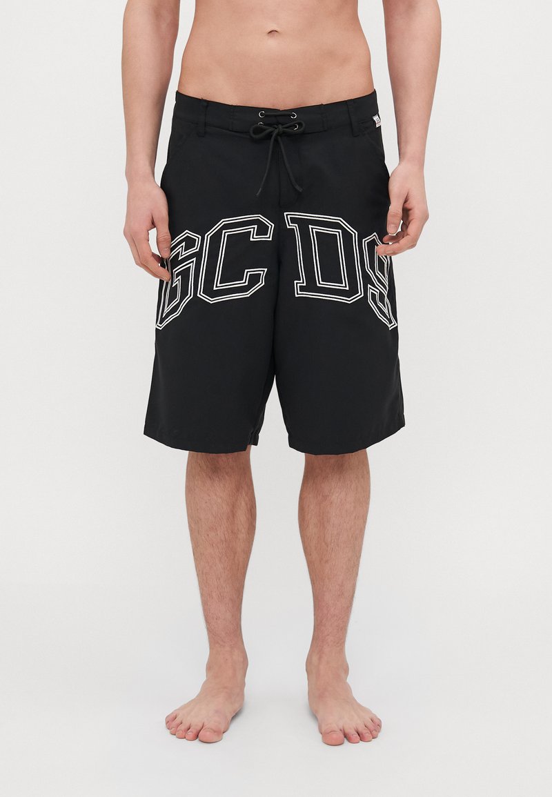 Černé plavky s elastickým pasem a šňůrkou, velkým bílým nápisem "GC DS" na každé noze a hladkým povrchem.