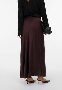 Bourgogne satin maxi-nederdel, glat tekstur, elegant fald. Parret med en sort plisseret bluse og sort clutch, der fremhæver spidse tå hæle.