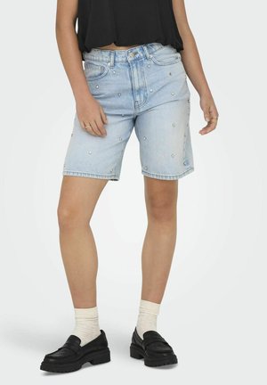 Shorts en denim bleu clair avec des clous argentés, longueur mi-cuisse, design classique à cinq poches, associés à des mocassins noirs et des chaussettes blanches de style crew.